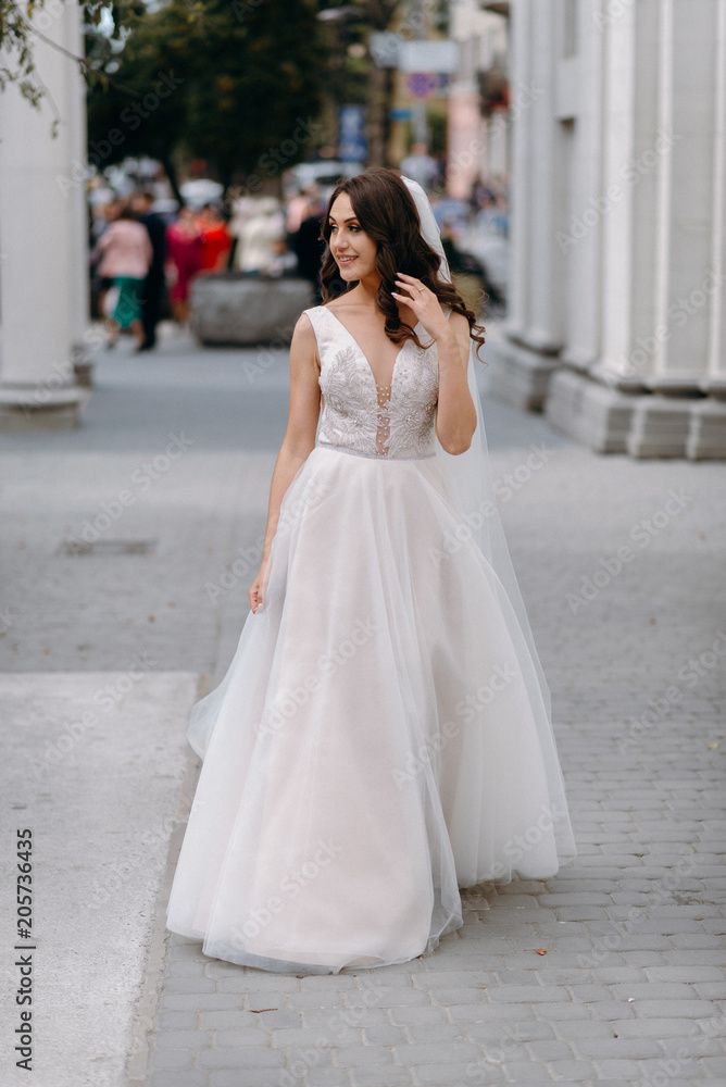 Portrait of a beautiful bride with a bouquet in her hands on a wedding day against a white wall. Portrait of a beautiful bride with a bouquet in her hands on a wedding day against a white wall.