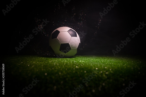 Traditional soccer ball on soccer field. Close up view of soccer ball  football  on green grass with dark toned foggy background.