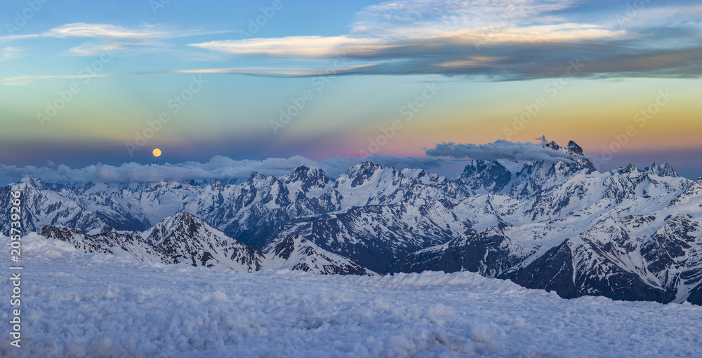 snowy Caucasus mountains at sunset with moonrising and Anticrepuscular rays