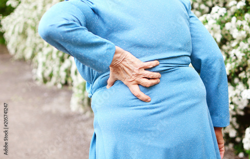 Backache. Aged woman with back pain. Elderly woman goes to doctor. . photo