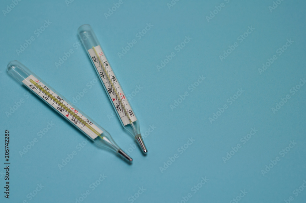 Two glass mercury thermometers on blue background with copy space Two glass mercury thermometers on blue background with copy space