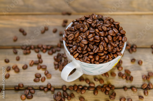Coffee beans in a cup standing on a wooden background