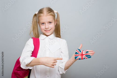 little schoolgirl with a painted British flag on his hand, portrait on a gray background