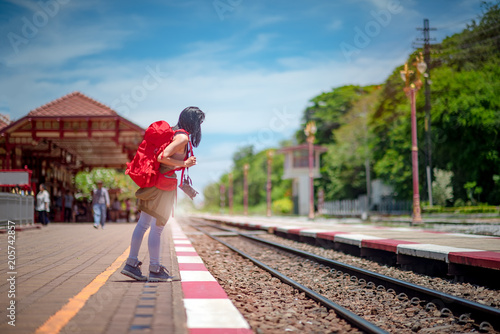 woman standing on the railway station looking for the incoming train, find destination for tourist traveling in holiday vacation