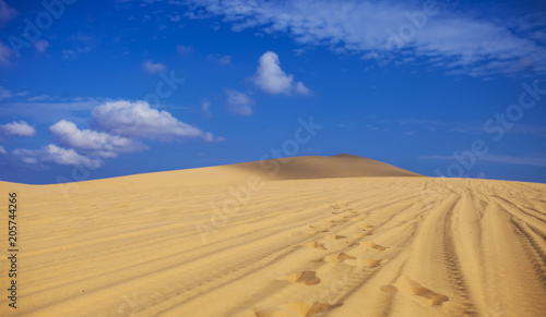 Sand dunes near Mui Ne. Group of off roads on top of dunes in the background. Sunny day with blue sky and clouds