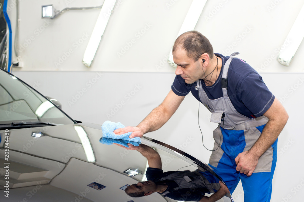 A man polishes a black car with a polisher A man polishes a black car with a polisher