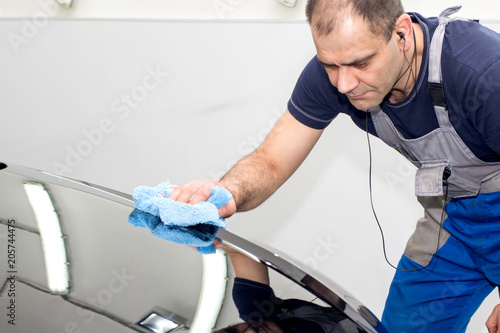 A man polishes a black car with a polisher