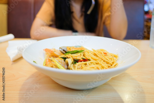 Spaghetti in white plate on wooden table.