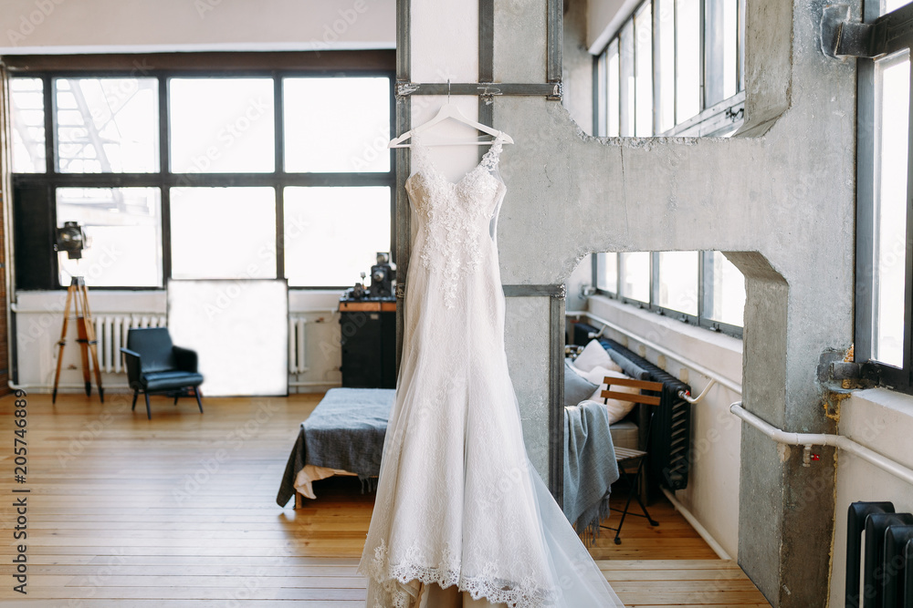 Beautiful women wedding dress weighs on the hangers in the big hall on the wall