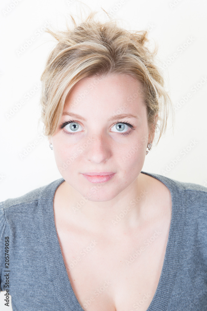 Young blonde woman in grey T-shirt looking at the camera on white background Young blonde woman in grey T-shirt looking at the camera on white background