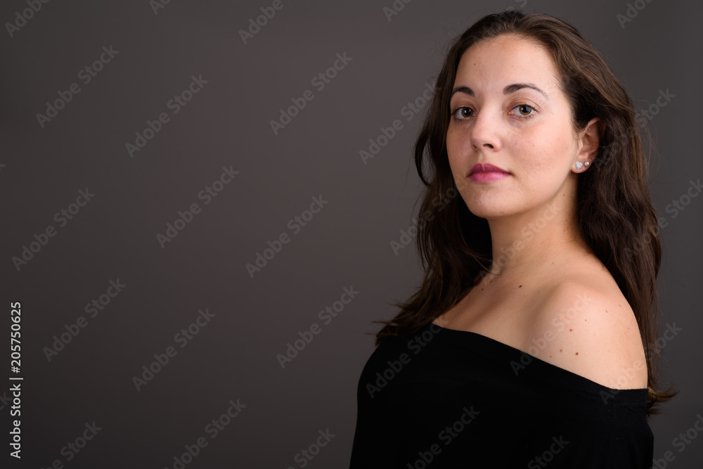 Naklejka premium Young beautiful woman wearing black off-shoulder top against gra