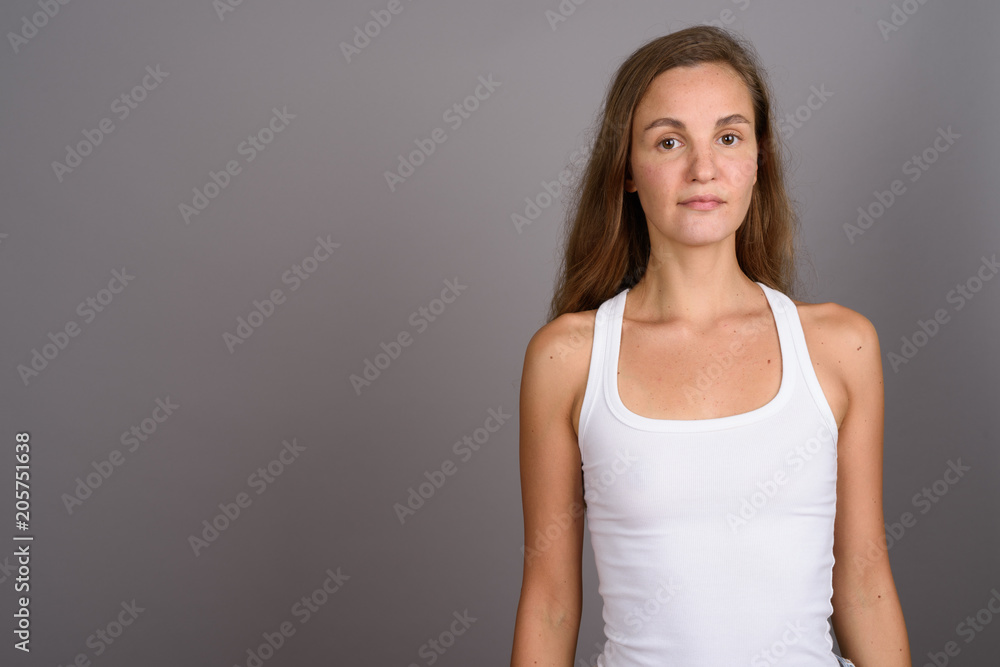 Young beautiful woman with long blond hair against gray backgrou Young beautiful woman with long blond hair against gray backgrou