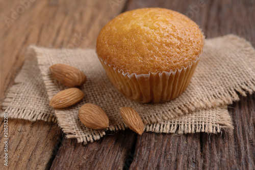 Close up a cup of almond cake against sack fabric on wooden table