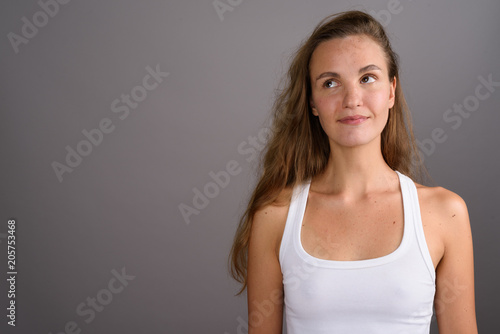 Young beautiful woman with long blond hair against gray backgrou