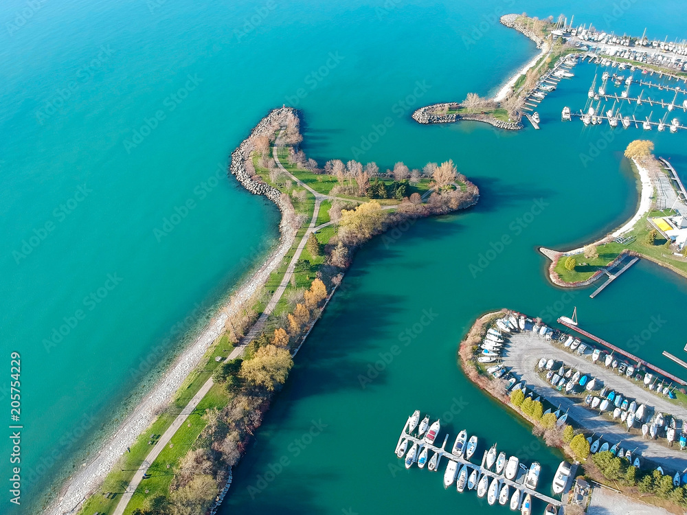Fototapeta premium Aerial view of sailing yachts and boats near wooden piers. Top view of American city large boat parking near sea coast. Island and parks with green grass. Beginning of summer concept.