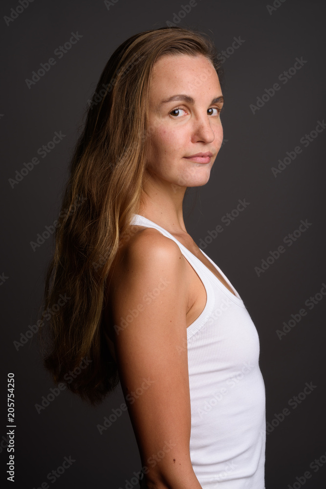Young beautiful woman with long blond hair against gray backgrou Young beautiful woman with long blond hair against gray backgrou
