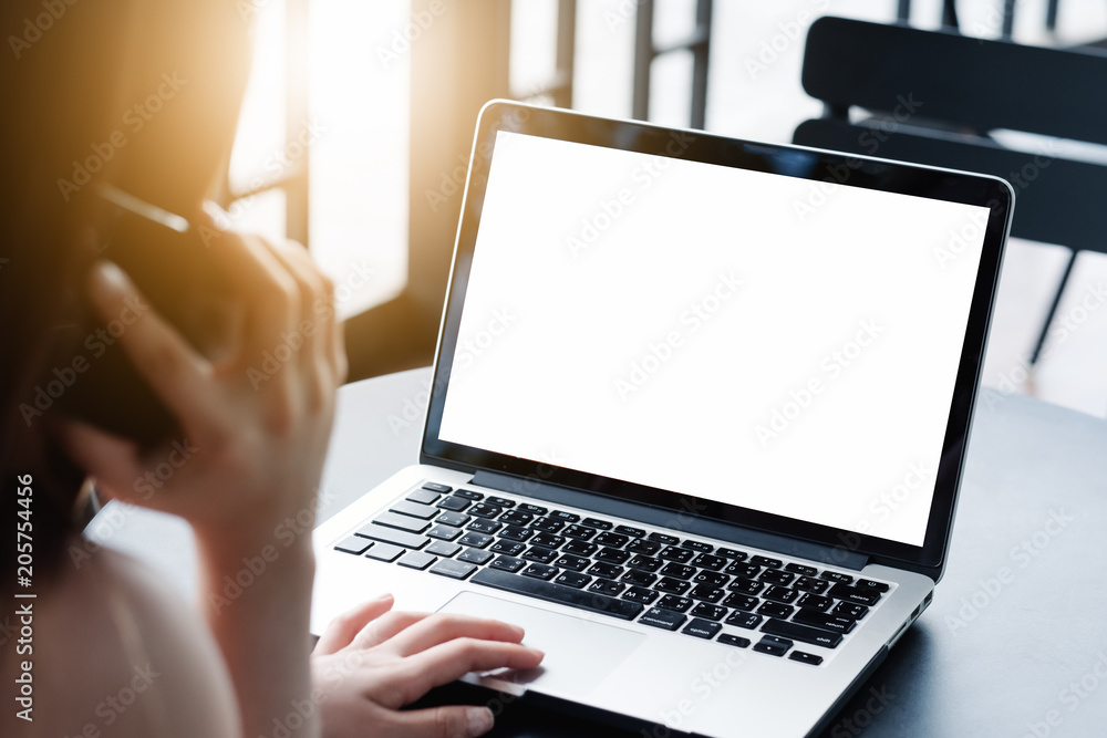 Mockup image of a businesswoman using laptop with blank white desktop screen with coffee cup on wooden table in cafe Mockup image of a businesswoman using laptop with blank white desktop screen with coffee cup on wooden table in cafe