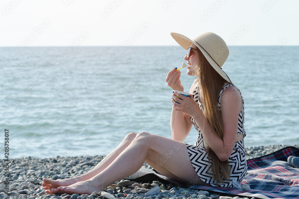 Girl in hat eating ice cream on the beach. sunny day