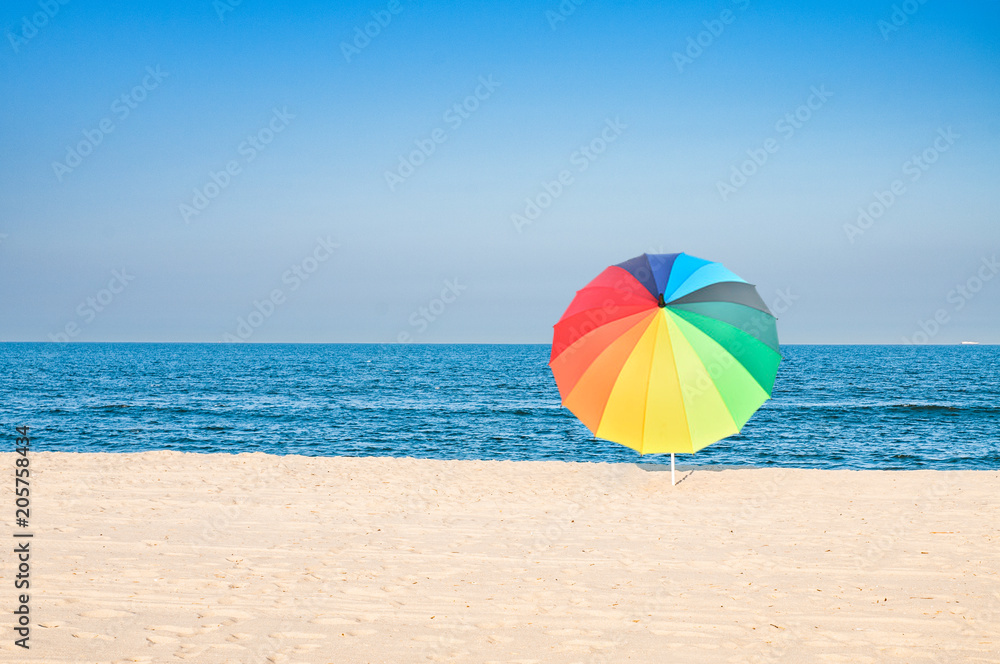 Colored umbrella on beach with white sand and blue sky