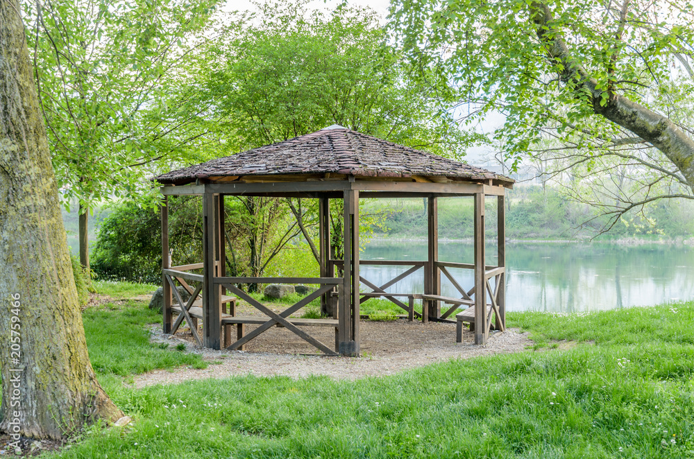 A wooden gazebo with a tiled roof on the bank of the Adda river in Calolziocorte A wooden gazebo with a tiled roof on the bank of the Adda river in Calolziocorte