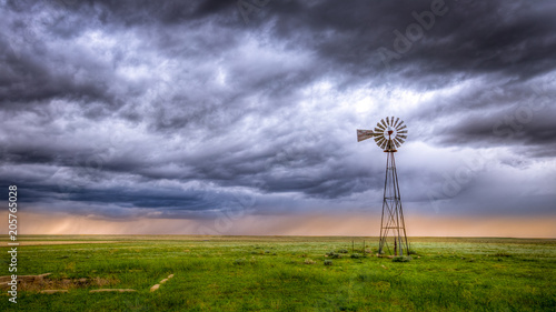 Windmill on a farm in an open field under a dramatic sky