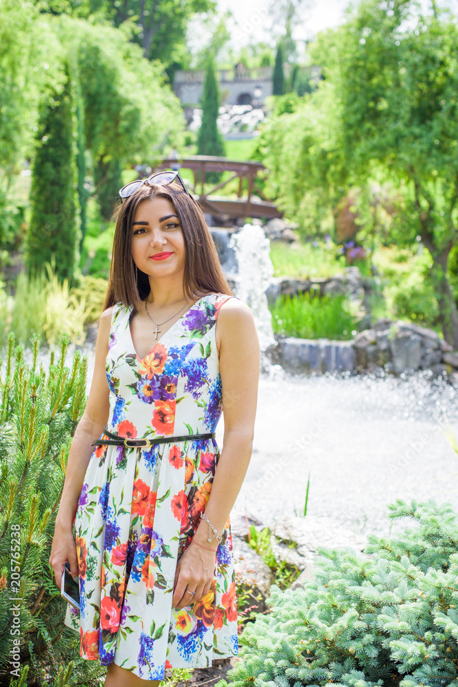 Hispanic pretty young woman rest at summer time. Latina Woman wear flowers print dress relax at nature and enjoy the life Hispanic pretty young woman rest at summer time. Latina Woman wear flowers print dress relax at nature and enjoy the life
