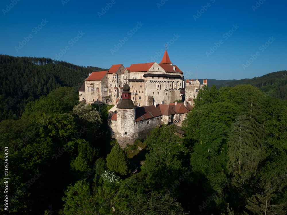 Moravian castle Pernstejn, standing on a hill above deep forests of the Bohemian-Moravian Highlands against blue sky. Aerial photography. Ancient royal castle in Czech landscape, czech travel place.