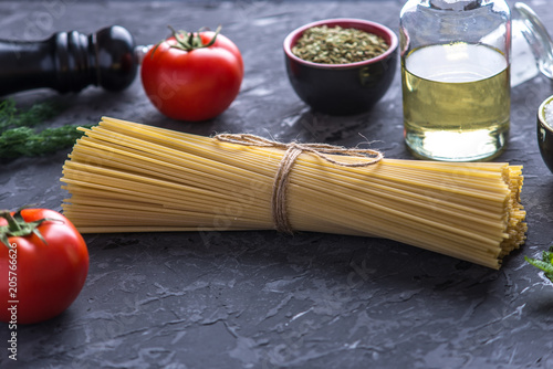 Uncooked pasta spaghetti with ingredients for tomato sauce. Concept of the composition of food design.