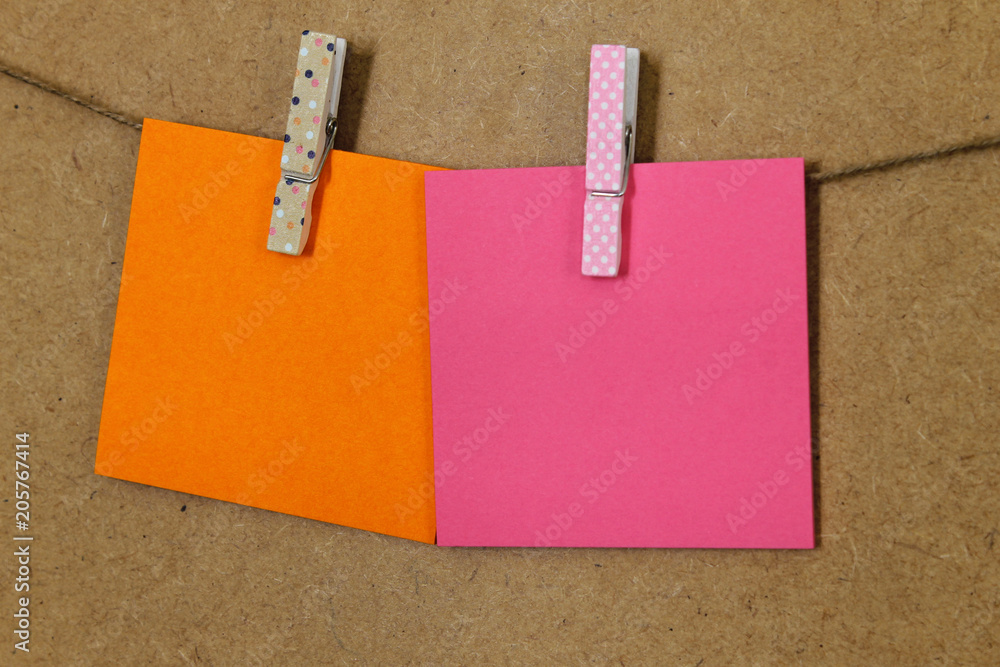  Hoja de papel de color rosa y naranja (posit), sujeto con pinzas de colores y dibujos, en una cuerda a la pared de corcho 素材庫相片