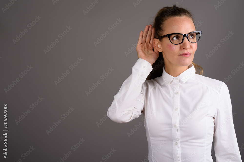 Young beautiful businesswoman against gray background