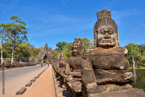 The entrance to Angkor Thom.There are statues on both sides and cars running through.
