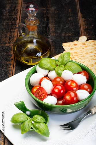 Italian soft cheese, young small balls mozzeralla cheese salad served with fresh basil, tasty ripe cherry tomatoes and Italian olive oil photo