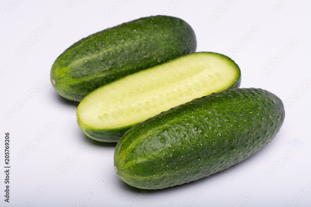 Fresh small green cucumbers whole and sliced close up copy space isolated on white background Fresh small green cucumbers whole and sliced close up copy space isolated on white background