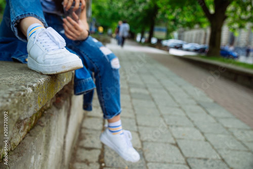 woman sitting on parapet at street. resting after walk. body part