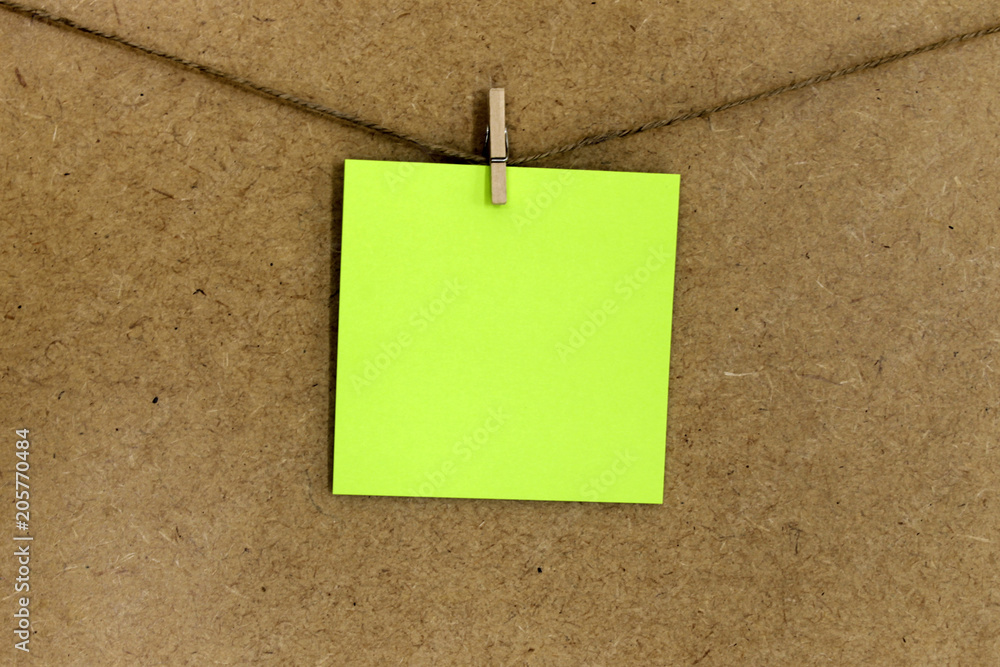 Hoja de papel de color verde (posit), sujeto con una pequeña pinza de madera y una cuerda a una pared de corcho. Hoja de papel de color verde (posit), sujeto con una pequeña pinza de madera y una cuerda a una pared de corcho.
