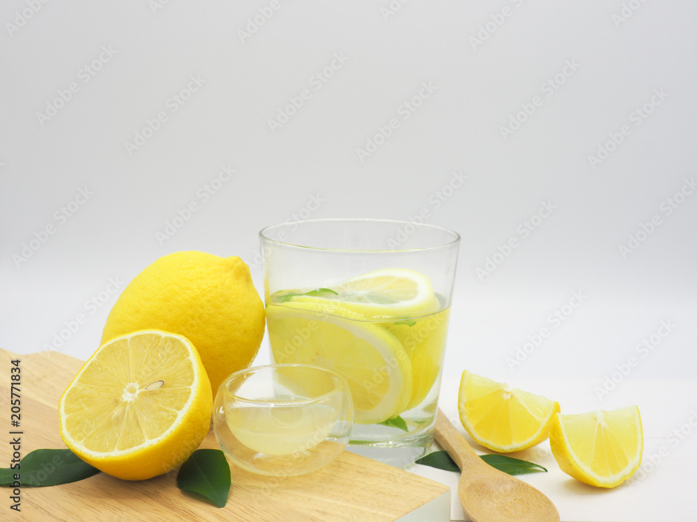 Fresh lemon in water, lemonade and lemon slice on white wood background Fresh lemon in water, lemonade and lemon slice on white wood background