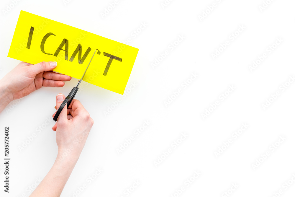 I can concept. Motivate youself, believe in yourself. Hand cut off the letter t of written word I can't by sciccors. White background top view copy space I can concept. Motivate youself, believe in yourself. Hand cut off the letter t of written word I can't by sciccors. White background top view copy space