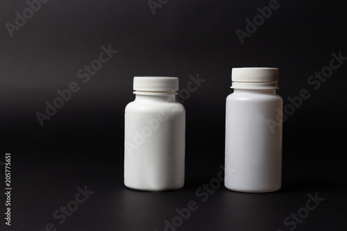 two white pill bottles on black background. horizontal