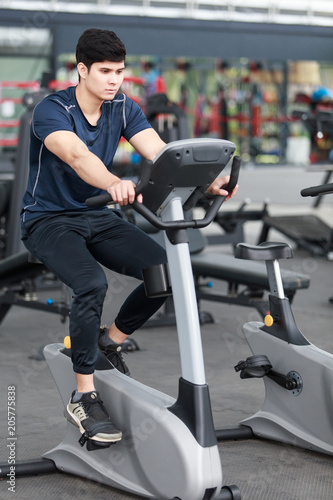 Footage of a man working out in gym on the exercise bike, young man cycling in the gym.