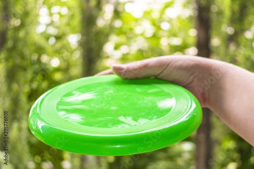 hand throwing a frisbee disc in the park on a summer day