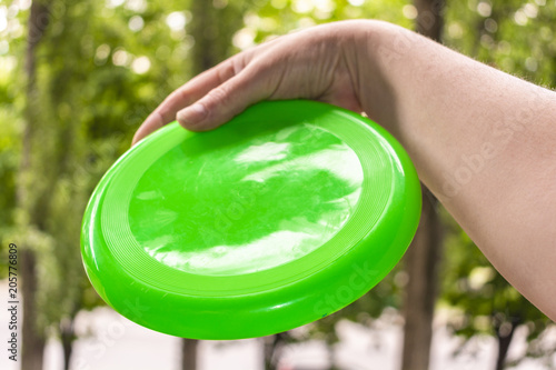 hand throwing a frisbee disc in the park on a summer day