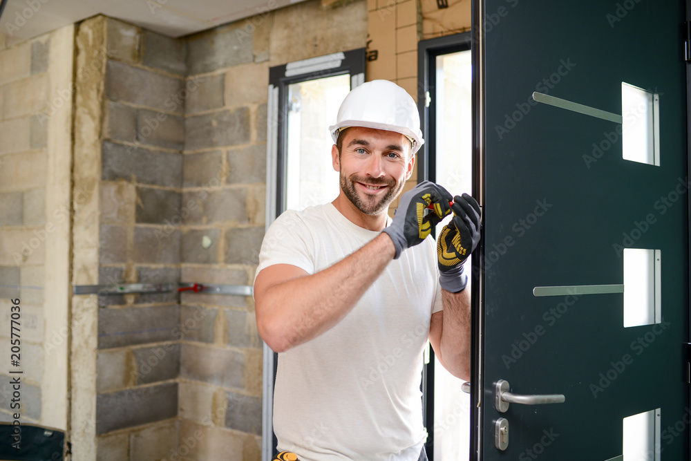 handsome young man installing a door in a new house construction site