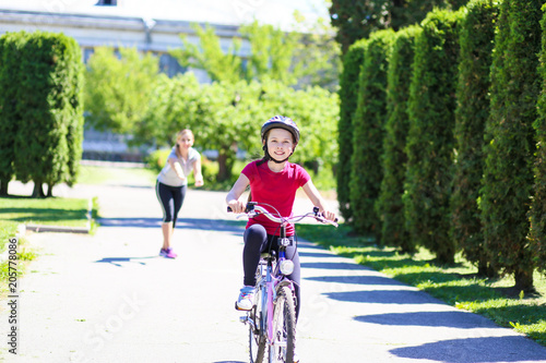 Wallpaper Mural the parent teaches riding a two-wheeled child bike in the park. Mom and daughter spend time together. Torontodigital.ca