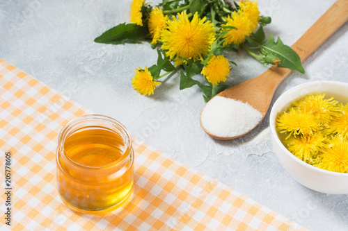 Ingredients for jam from dandelions. Fresh flowers of dandelions  sugar and water on a light summer background.