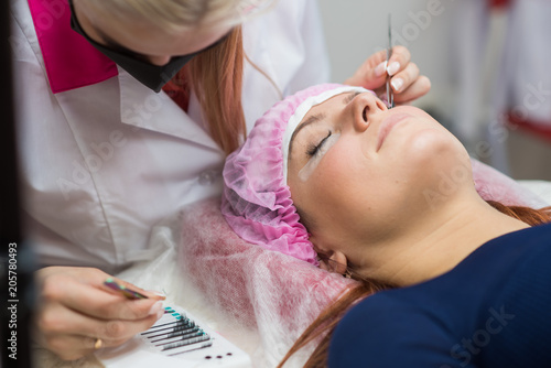 Professional beautician undergoing eyelash extension procedure. Master and a client in a modern beauty salon