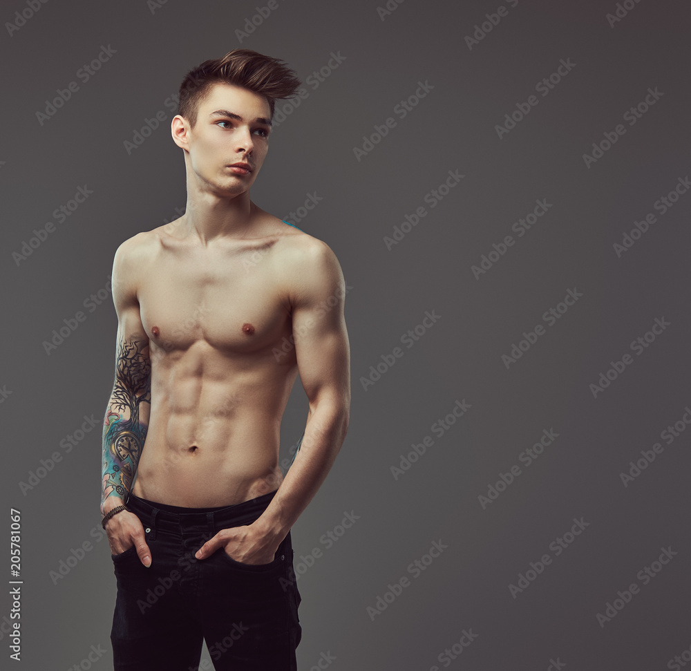 Handsome shirtless tattoed guy with stylish hair posing in a studio.