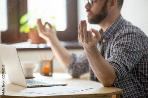 Foto Concentrated male worker meditating, relieving stress, person taking break from work trying to find balance, keep thoughts in order, calm down