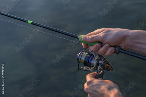 Hands of fisherman with fishing spinning rod