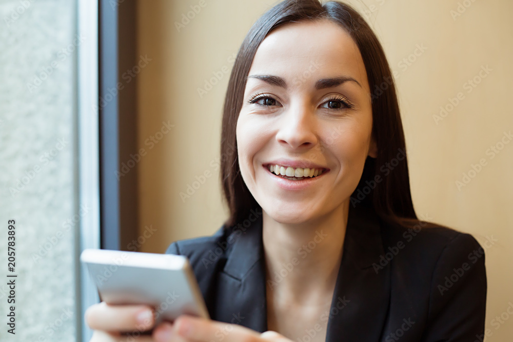 Happy woman with phone at cafe smiling and looking on camera Happy woman with phone at cafe smiling and looking on camera