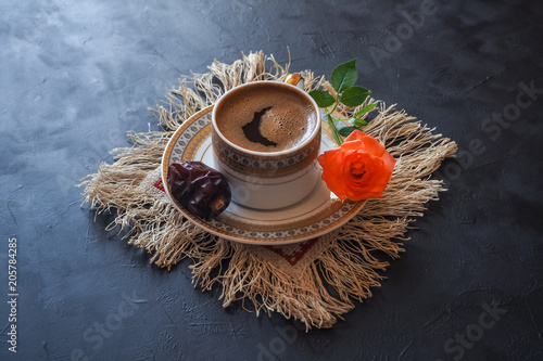 Black coffee and dates on the black table. Sweet food for Ramadan.  photo